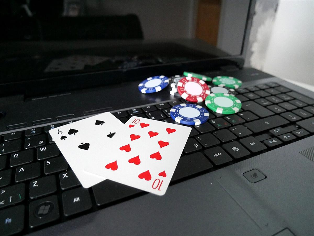 Laptop dengan kartu dan keripik poker di atas meja