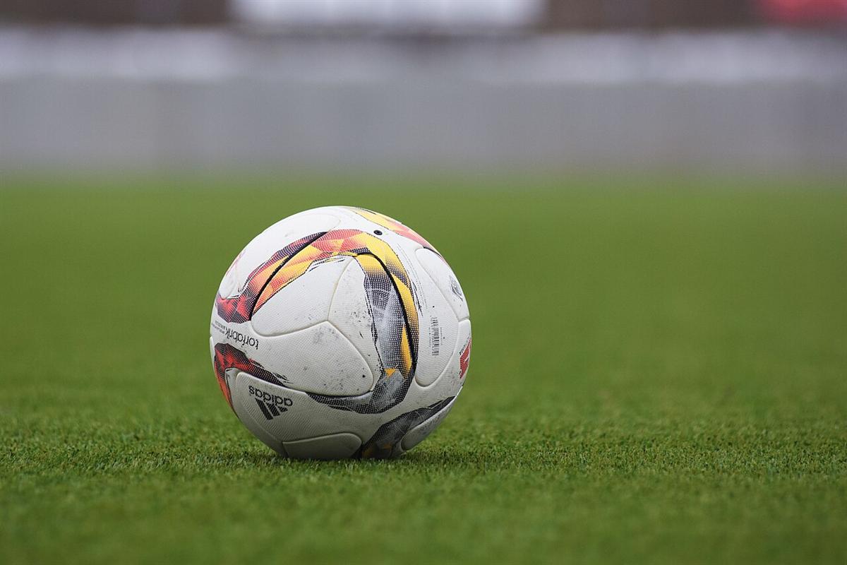Bola sepak tergeletak di atas lapangan rumput hijau